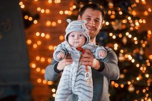 Vater mit seinem Kind zusammen im weihnachtlich dekorierten Zimmer foto