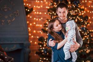 vater und mutter mit ihrem kind zusammen im weihnachtlich dekorierten zimmer foto