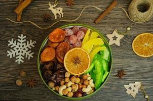 nüsse, getrocknete früchte in einer schachtel mit weihnachtsschmuck auf dem tisch foto