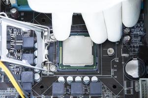 Draufsicht auf Motherboard und Techniker beim Einsetzen des CPU-Chips. foto