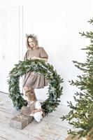 eine junge frau mit blonden haaren und eine kleine tochter mit einem weihnachtskranz. neujahrskonzept, weihnachtsschmuck foto