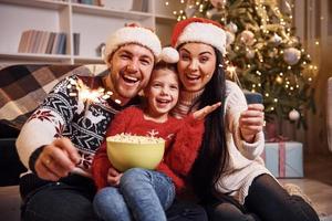 glückliche familie drinnen in weihnachtsmützen haben spaß zusammen und feiern das neue jahr foto