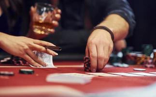 Nahaufnahme der eleganten Hände junger Menschen, die im Casino Poker spielen foto