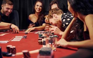 Gruppe eleganter junger Leute, die zusammen im Casino Poker spielen foto