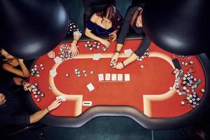 Draufsicht auf elegante junge Leute, die im Casino Poker spielen foto