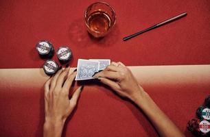 Draufsicht auf die Hände der Frau. Mädchen spielt Pokerspiel am Tisch im Casino foto