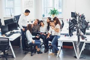 gruppe junger mitarbeiter, die im büro an einem neuen projekt sprechen und arbeiten foto