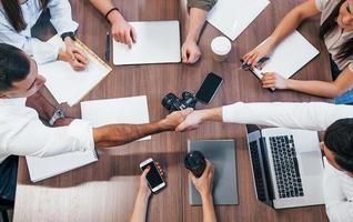 Draufsicht auf junge Geschäftsleute, die im modernen Büro mit Dokumenten und Laptop zusammenarbeiten foto