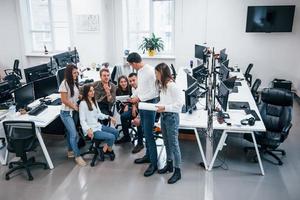 Gruppe junger Geschäftsleute, die im Büro stehen und sitzen und arbeiten foto