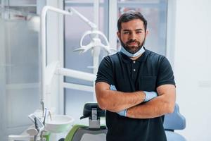 Porträt des Zahnarztes in Handschuhen, der drinnen in der Klinik steht foto