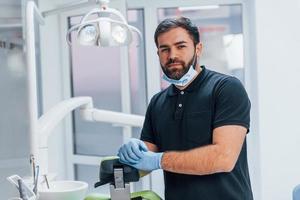 Porträt des Zahnarztes in Handschuhen, der drinnen in der Klinik steht foto
