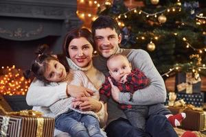 schönes kaukasisches paar, das weihnachten zuhause mit ihrem kleinen sohn und ihrer tochter feiert foto