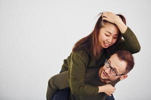 glückliches multiethnisches paar in lässiger kleidung hat drinnen im studio spaß zusammen. Kaukasier mit asiatischer Freundin foto