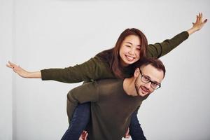 glückliches multiethnisches paar in lässiger kleidung hat drinnen im studio spaß zusammen. Kaukasier mit asiatischer Freundin foto