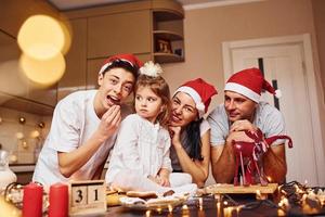 festliche familie in weihnachtsmützen viel spaß in der küche und beim zubereiten von essen foto