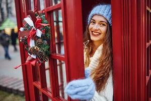 frau in warmer kleidung hat spaß in der telefonstation. schönes Mädchen foto