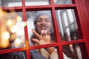 frau in warmer kleidung hat spaß in der telefonstation. Blick durch das Glas foto