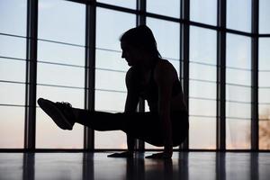 Silhouette einer jungen sportlichen Frau in Sportbekleidung, die Fitness im Fitnessstudio macht foto