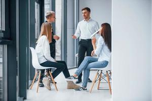 Eine Gruppe junger erfolgreicher Teams arbeitet und kommuniziert drinnen im Büro in der Nähe von Fenstern foto