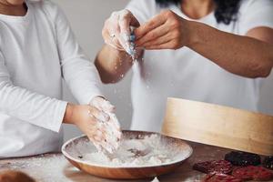 Nahaufnahme einer Frau mit ihrer Enkelin, die in der Küche Essen mit Mehl zubereitet foto