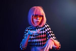 Porträt eines jungen Mädchens mit blonden Haaren in Brillen in rotem und blauem Neon im Studio foto
