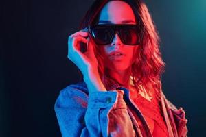 Porträt eines jungen Mädchens mit Sonnenbrille in rotem und blauem Neon im Studio foto