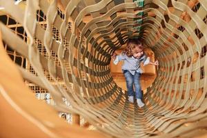 Kind hat Spaß im Spielzimmer, indem es durch den Holzkäfig geht foto