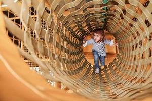 Kind hat Spaß im Spielzimmer, indem es durch den Holzkäfig geht foto