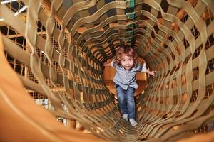 Kind hat Spaß im Spielzimmer, indem es durch den Holzkäfig geht foto