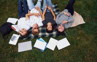 gute Erholung haben. Gruppe junger Studenten in Freizeitkleidung auf grünem Gras tagsüber foto