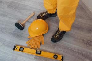 Werkzeuge auf dem Boden. Handwerker in gelber Uniform, der drinnen steht. haussanierungskonzept foto
