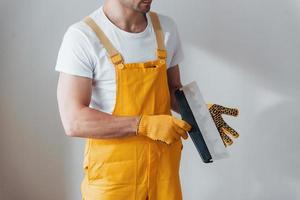 Handwerker in gelber Uniform, der an einer weißen Wand steht. haussanierungskonzept foto