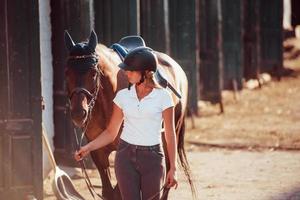 Reiterin in Uniform und schwarzem Schutzhelm mit ihrem Pferd foto