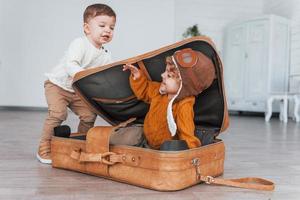 zwei kleine jungen haben spaß und sitzen tagsüber im koffer drinnen foto