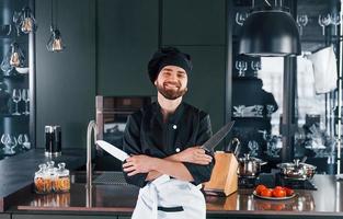 porträt eines professionellen jungen kochs in uniform, der in der küche für die kamera posiert foto