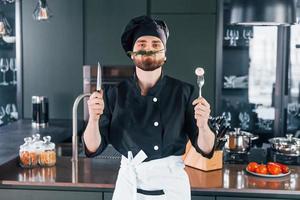 porträt eines professionellen jungen kochs in uniform, der in der küche für die kamera posiert foto