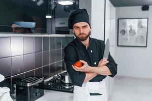 professioneller junger koch in uniform, der in der küche steht foto