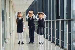 Schulkinder in Uniform zusammen mit Büchern im Korridor. Konzeption von Bildung foto