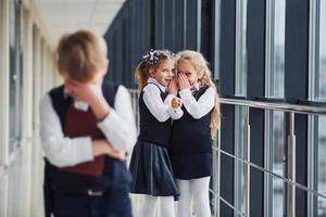 kleiner Junge wird gemobbt. Begriff der Belästigung. Schulkinder in Uniform zusammen im Korridor foto