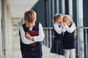 kleiner Junge wird gemobbt. Begriff der Belästigung. Schulkinder in Uniform zusammen im Korridor foto