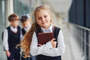 Schulkinder in Uniform zusammen mit Büchern im Korridor. Konzeption von Bildung foto