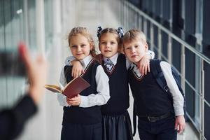 Schulkinder in Uniform machen gemeinsam ein Foto im Korridor. Konzeption von Bildung