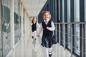 Schulmädchen in Uniform laufen im Korridor zusammen. Konzeption von Bildung foto