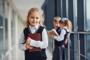 Schulkinder in Uniform zusammen mit Büchern im Korridor. Konzeption von Bildung foto