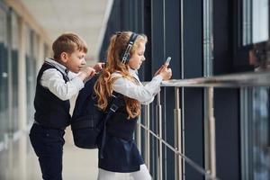 Ein kleiner Schuljunge stiehlt Dinge aus der Tasche eines Mädchens, während sie Musik hört foto