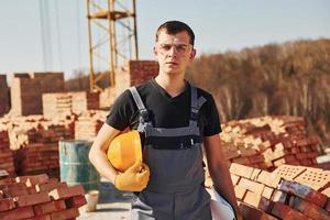 Porträt eines Bauarbeiters in Uniform und Sicherheitsausrüstung, der auf dem Dach eines unfertigen Gebäudes steht foto