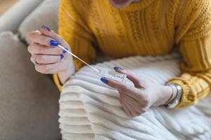 frau, die wattestäbchen verwendet, während sie zu hause einen coronavirus-pcr-test durchführt. Frau, die Coronavirus-Schnelldiagnosetest verwendet. junge frau zu hause, die einen nasentupfer für covid-19 verwendet. foto