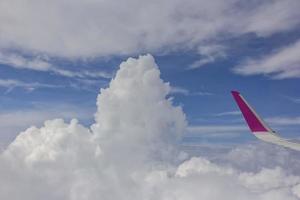 Blick aus dem Flugzeug. der Flügel eines Flugzeugs und erstaunliche weiße Wolken am blauen Himmel foto