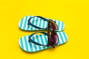 Gestreifte Flip-Flops mit Sonnenbrille auf gelbem Hintergrund, Sommerferien foto