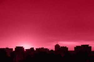 Silhouette der Stadt bei Sonnenuntergang. Stadtlandschaft im Morgengrauen. Farbe des Jahres 2023 - Viva Magenta foto